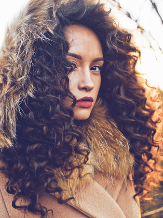 Outdoor fashion photo of young beautiful lady in autumn landscape. Beige coat, fur collar, wine lipstick. Fashion lookbook. Warm Autumn. Warm winterの写真素材