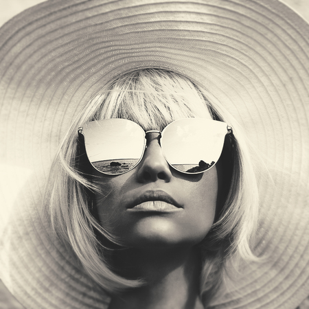Black and white outdoor fashion photo of young beautiful lady in hat and sunglasses. Summer Beach travel. Summer vibesの写真素材