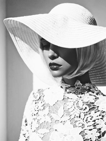 Black and white outdoor fashion photo of young beautiful lady in white hat. Summer Beach travel. Summer vibesの写真素材