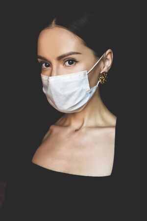 Lifestyle portrait of young beautiful lady with medical mask. Stay home. Coronavirus. Quarantine. Coronavirus pandemic in the worldの写真素材