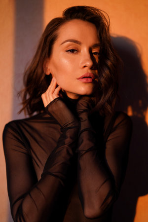 Athmospheric photo of gorgeous woman in transparent black dress. Sunset rays. Fashion dress