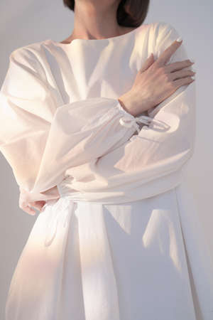 Pensive brunette in a white dress in the light of sunbeamsの写真素材