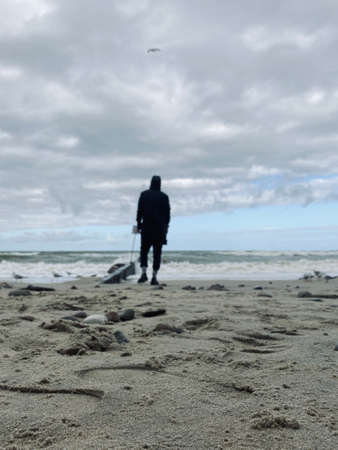 A lonely man stands on the beach and looks to the horizon.の写真素材