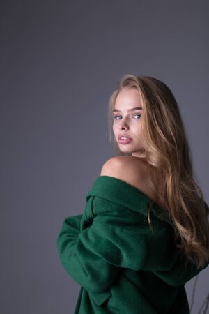 Gorgeous stylish blonde model posing in long luxurious green trench coatの写真素材