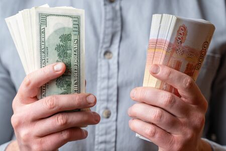 Male hands hold money dollars and Russian 5000 rubles. Crisis concept. High exchange rates, depreciation of moneyの写真素材