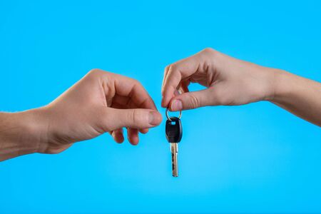 Close up cropped man woman hands present give each other gift car keys isolated on pastel blue background in studio. Birthday holiday valentine day emotions celebration concept. Mock up copy spaceの写真素材