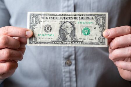 Man showing in front a one dollar banknote, holding on hands, concept designの写真素材