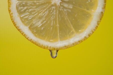 Close up or macro of a slice of lemon, a drop of water falls in slow motion. Concept of fresh fruit, cocktail.の写真素材