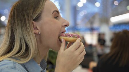 Young woman eating donut at the Mallの写真素材