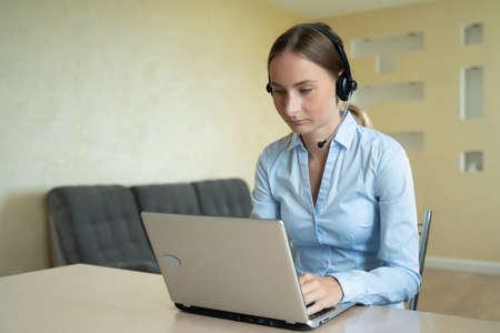 Woman wear headset communicating by conference call speak looking at computer at home office, video chat job interviewの写真素材