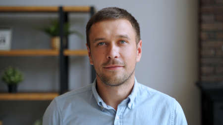 Portrait of young man smiling in house looking at camera standing alone. People, positive emotions and lifestyle concept.の写真素材