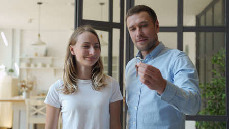 Happy couple receiving apartment key from real estate agent. Happy couple smiling and getting keys from new real estate from agent.の写真素材
