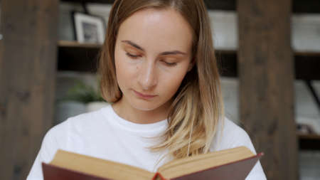 Beautiful young woman reading a book on the sofa.