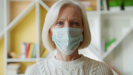 Safety and pandemic concept - portrait of senior woman wearing protective medical mask for protection from virus indoorsの写真素材