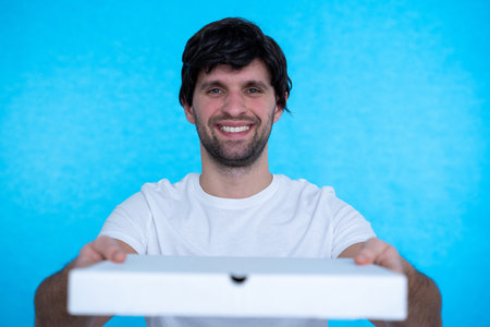 Man holding pizza boxes over isolated blue wall with happy expression