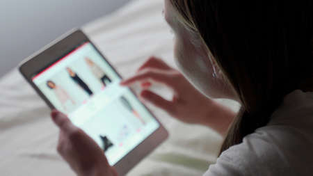 Woman looks at the page on the tablet. A woman looks at fashion trends on a tablet. The screen is...