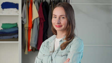 Portrait of a woman who stands against the background of a large wardrobe a wardrobe with stylish...