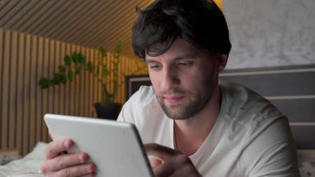 Man lying on bed using digital tablet