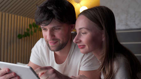Young couple using tablet on bed in bedroom late at night