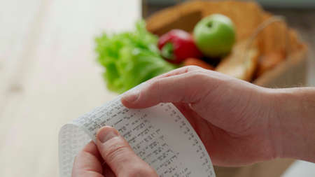 Close-up woman looking a check from a supermarket. Expense tracking and budgeting