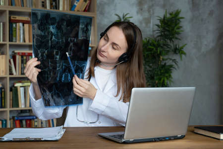 Woman doctor in headset explaining x-ray image to patient during video call