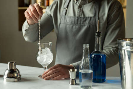 Professional man bartender stirring ice in the glass on the bar counterの写真素材