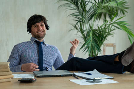 Businessman listening to music with earbuds and playing on imaginary guitar in office