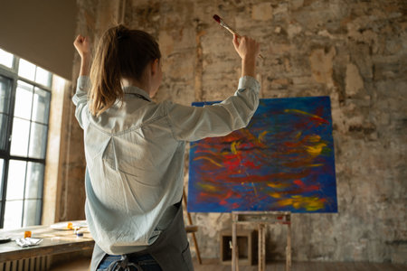 Female artist rejoices at the end of the work, raising her hands up