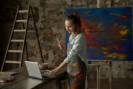 Female artist draws a picture and conducts a remote drawing training class. Woman shows that she draws, and teaches her studentsの写真素材