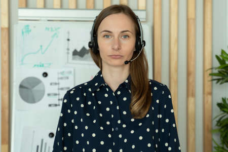 Young woman in a headset, standing in an office, working as a call center or support service...