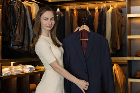 The saleswoman smiles and shows the clothes in the costume shop and speaks to the camera