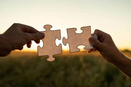 New idea and system. Womens hands assemble a puzzle against the background of the sunsetの写真素材