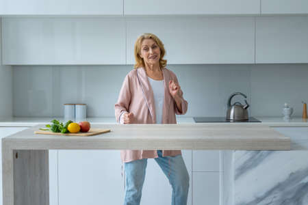 Happy senior woman dancing in kitchen, Elderly retirement female with happiness expressionの写真素材