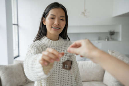 Young Asian woman gets the keys to the house and signs a contract with a real estate agencyの写真素材