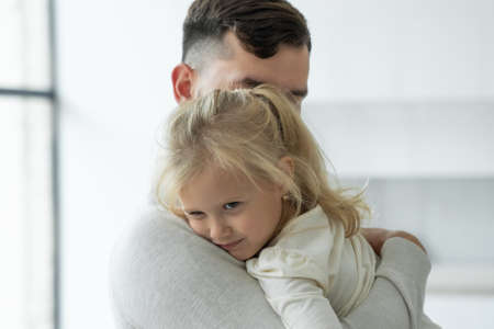 Portrait of a cute little girl in her fathers arms. A father and his daughter, a baby girl, play...