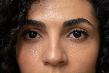 Close-up portrait of happy eyes of a brunette with curly hair looking into the camera, close-up of...