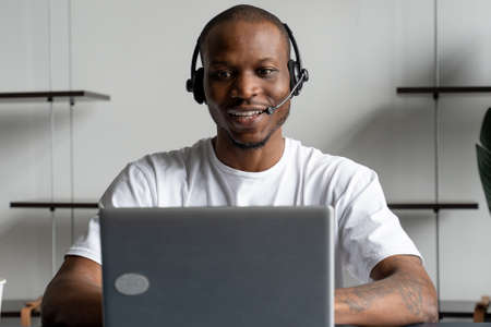A black man is a customer service operator with a hands-free headset working in an office.の写真素材