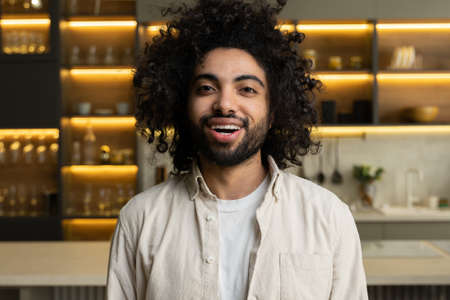 Cheerful Arabian man smiles looking in camera in kitchen