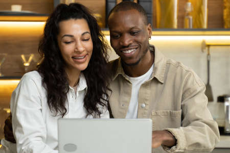 Young couple in love watch photos in laptop at kitchen tableの写真素材