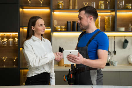 Foreman shows woman plan of kitchen renovation in tablet