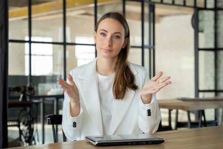 Confident businesswoman looking and talking through a webcam during a video conference from the office.の写真素材