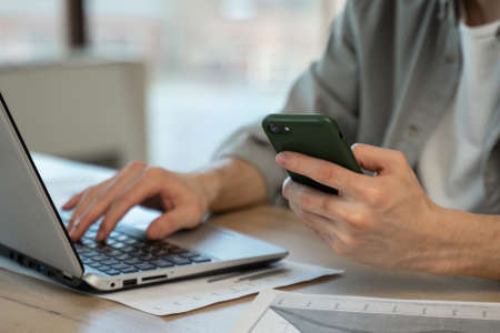 Young assistant types personal details to clients on laptop