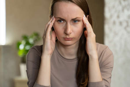 Tired business woman with a headache in the office, feels bad at work.