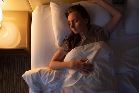 Young woman tries to fall asleep tossing and turning in bed at night. Sleepless lady lies in hotel...
