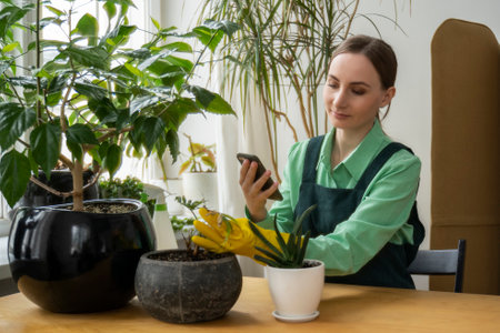Woman taking care of her plants and using her smartphone.の写真素材