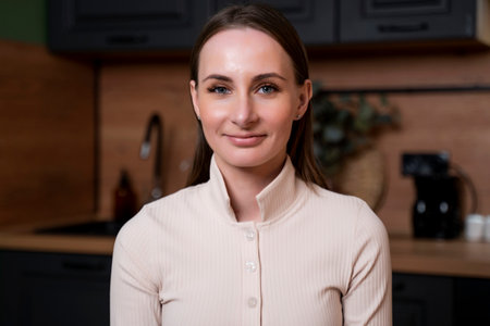 Young beautiful modern woman stand near table on kitchen at homeの写真素材