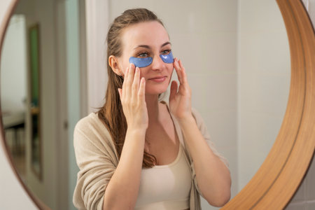 Pretty girl without makeup touches her face and smiles, using patches under her eyes to remove dark circles, giving the skin freshness.の写真素材