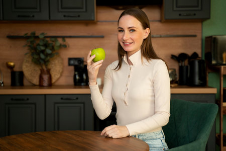 Happy young woman is eating an apple in the kitchen. Diet. The concept of a diet. Healthy food.の写真素材