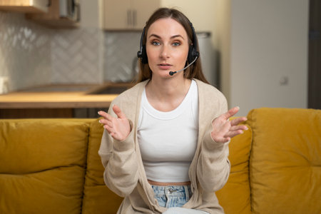 Hotline operator. Portrait of a friendly customer service representative wearing headphones in a call center, looking into the camera and smilingの写真素材