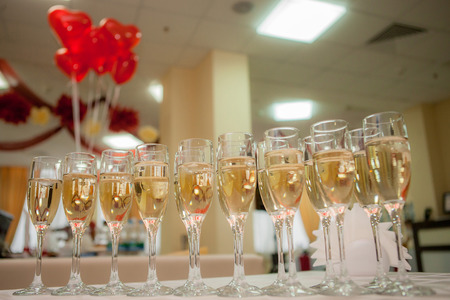 row of glasses of champagne with valentines hearts on backgroundの写真素材